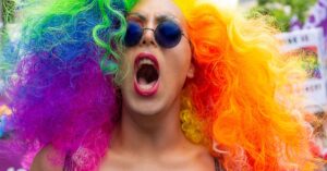 Colorful participant with rainbow wig and sunglasses at Brussels Pride Parade.